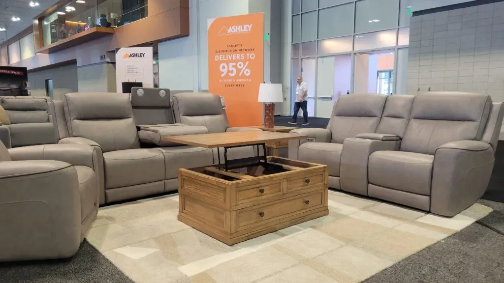 Ashley furniture booth at an expo with taupe sectional and coffee table